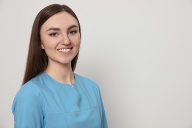 Photo of Happy nurse in medical uniform on white background, space for text