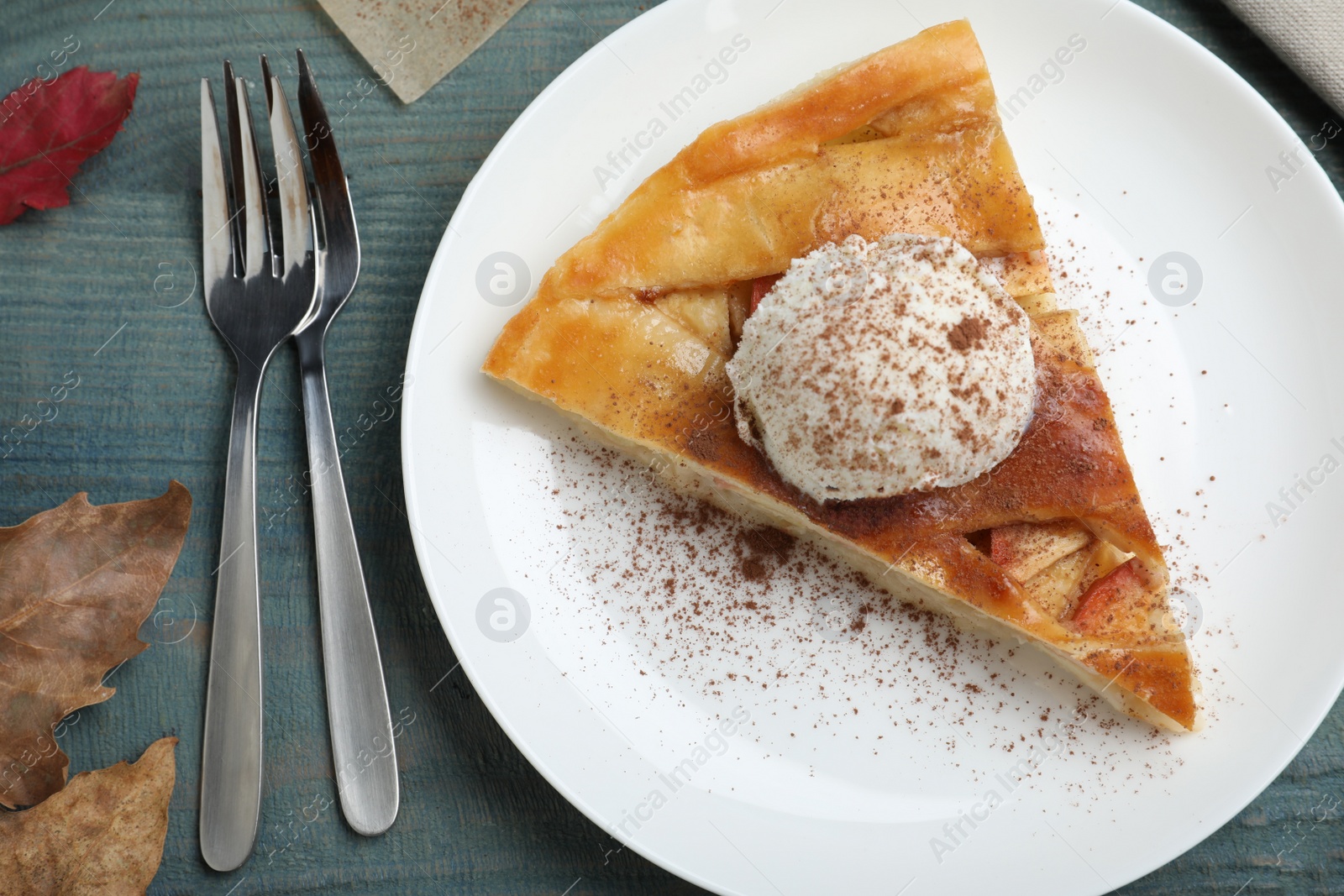 Photo of Slice of traditional apple pie with ice cream served on blue wooden table, flat lay