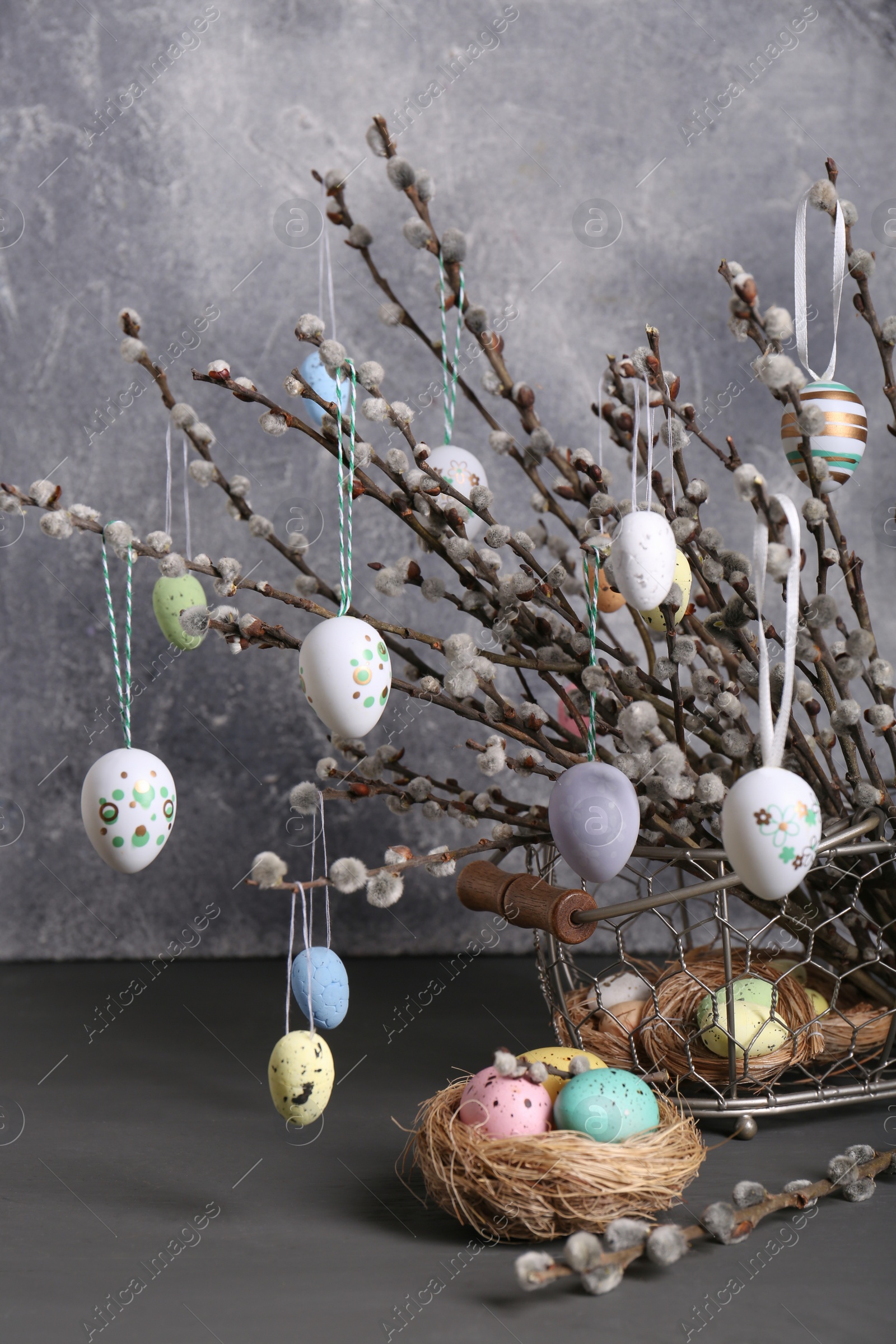 Photo of Beautiful willow branches with painted eggs and Easter decor on light grey wooden table