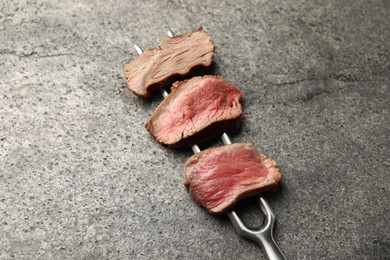 Photo of Delicious sliced beef tenderloin with different degrees of doneness on grey table