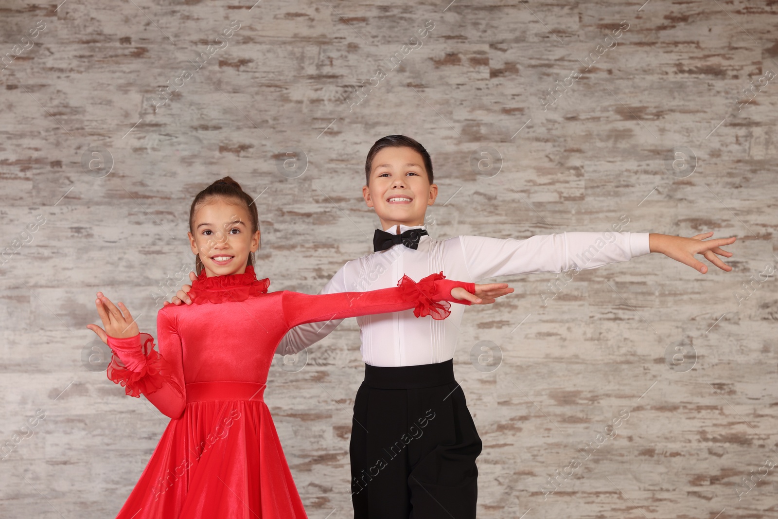 Photo of Beautifully dressed couple of kids dancing together in studio