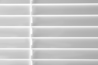 Photo of Closed modern white window blinds as background, closeup view