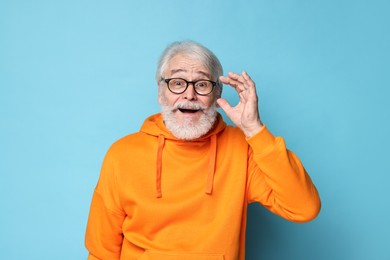 Senior man with mustache on light blue background