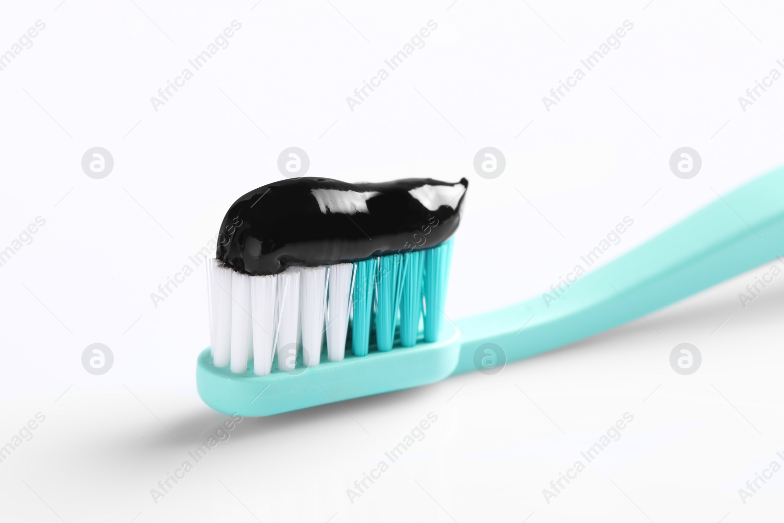 Photo of Brush with charcoal toothpaste on white background