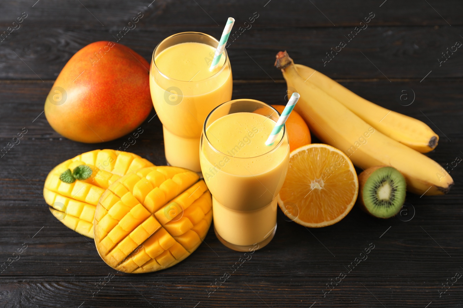 Photo of Tasty tropical drink with mango and fresh fruits on wooden table