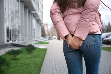 Woman suffering from hemorrhoid pain outdoors, closeup