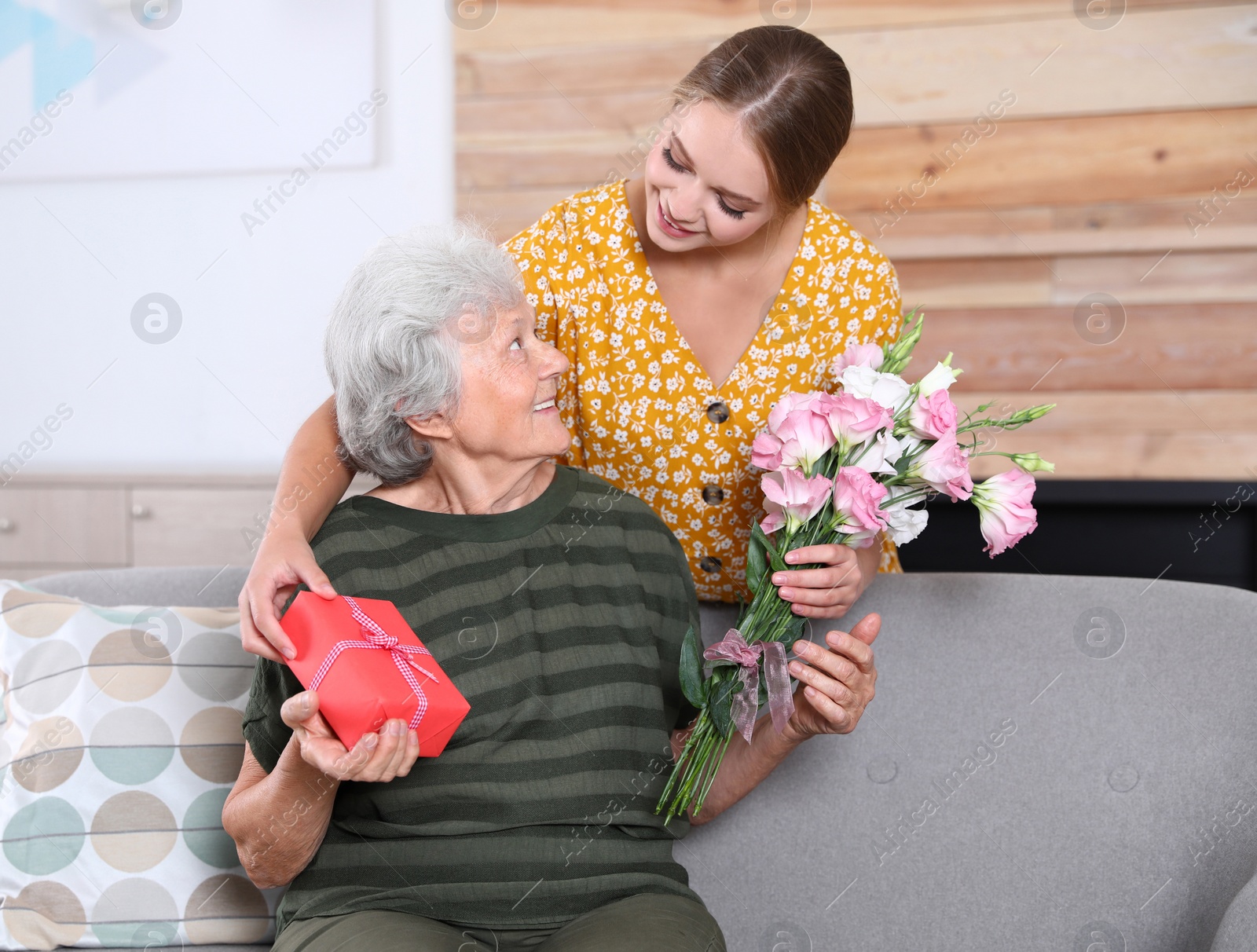 Photo of Young woman congratulating her senior mom at home. Happy Mother's Day