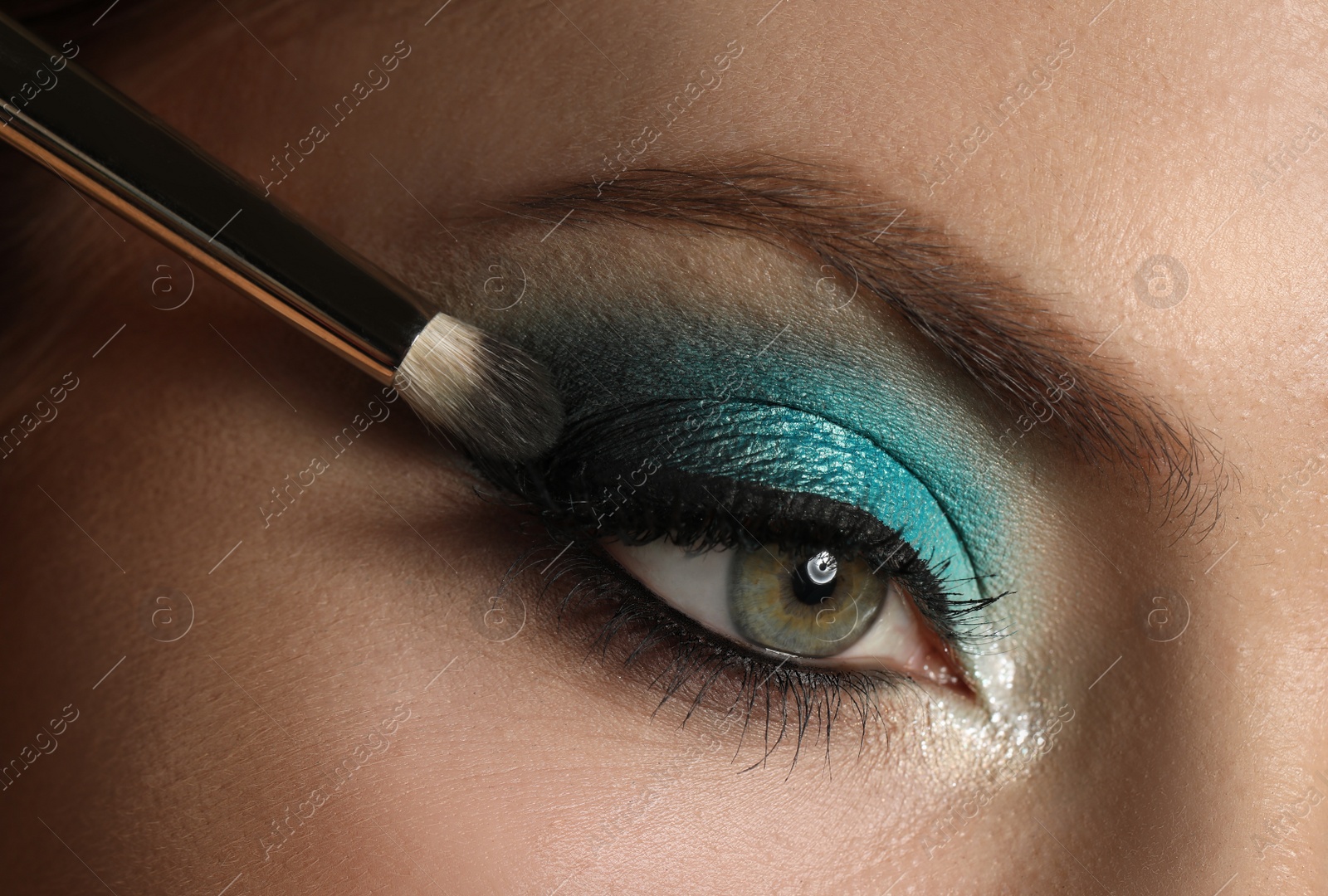 Photo of Applying eye shadow onto woman's face, closeup. Beautiful evening makeup