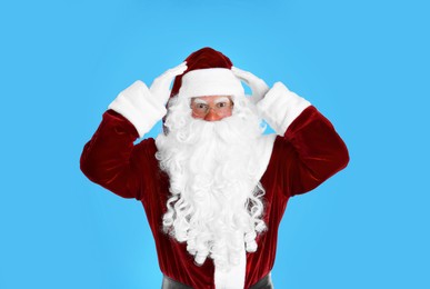 Photo of Portrait of emotional Santa Claus on light blue background