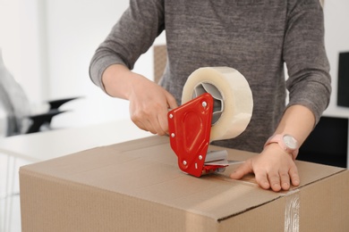 Young woman packing moving box indoors, closeup