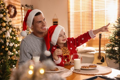 Happy father and his daughter with delicious Christmas cookies at home
