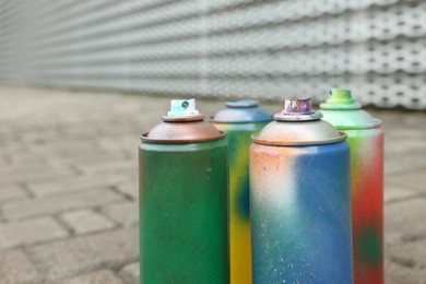 Used cans of spray paints on pavement, closeup