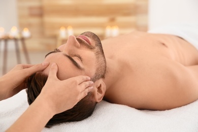 Handsome man receiving face massage in spa salon