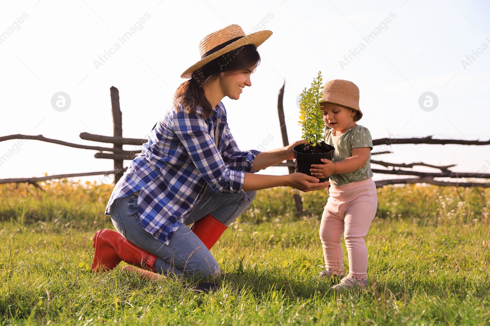 Photo of Mother and her baby daughter planting tree together in countryside