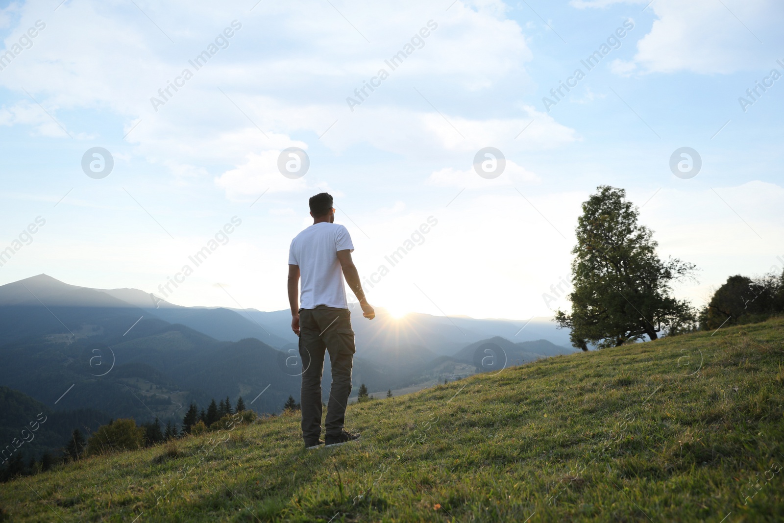 Photo of Man enjoying beautiful mountain landscape at sunset, back view
