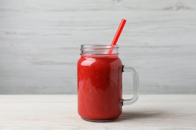 Photo of Mason jar with delicious berry smoothie on white wooden table