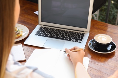 Photo of Woman writing blog content in notebook at table, closeup