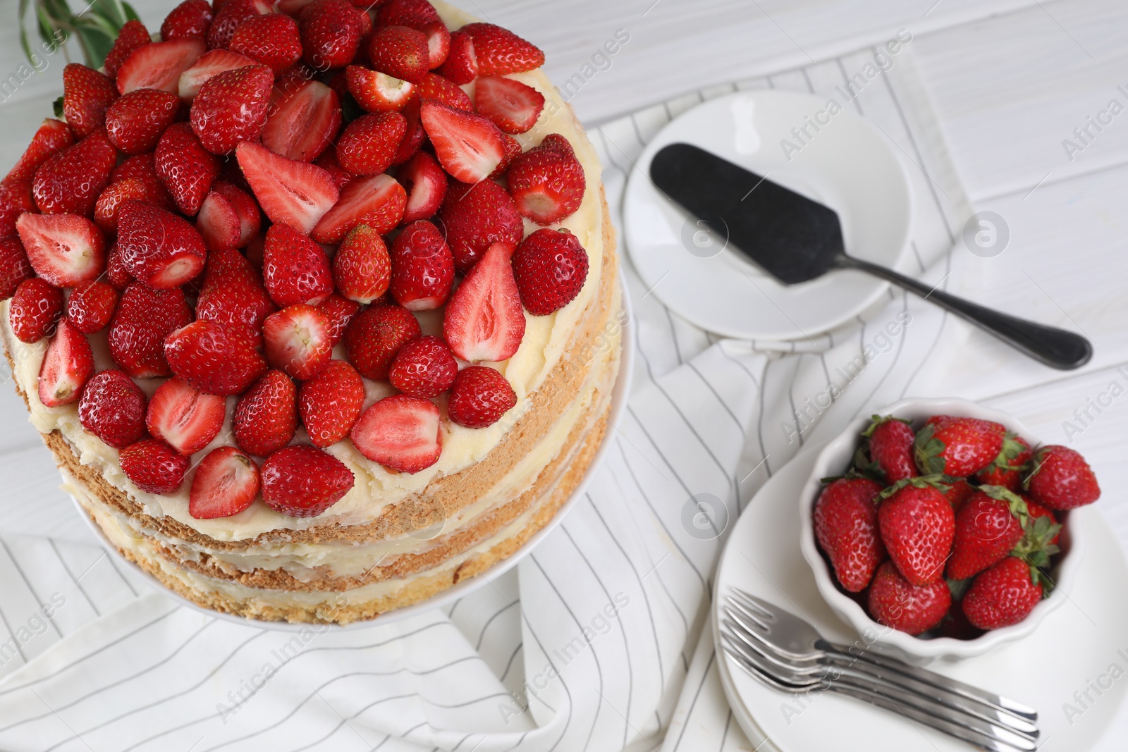 Photo of Tasty cake with fresh strawberries served on white table, above view