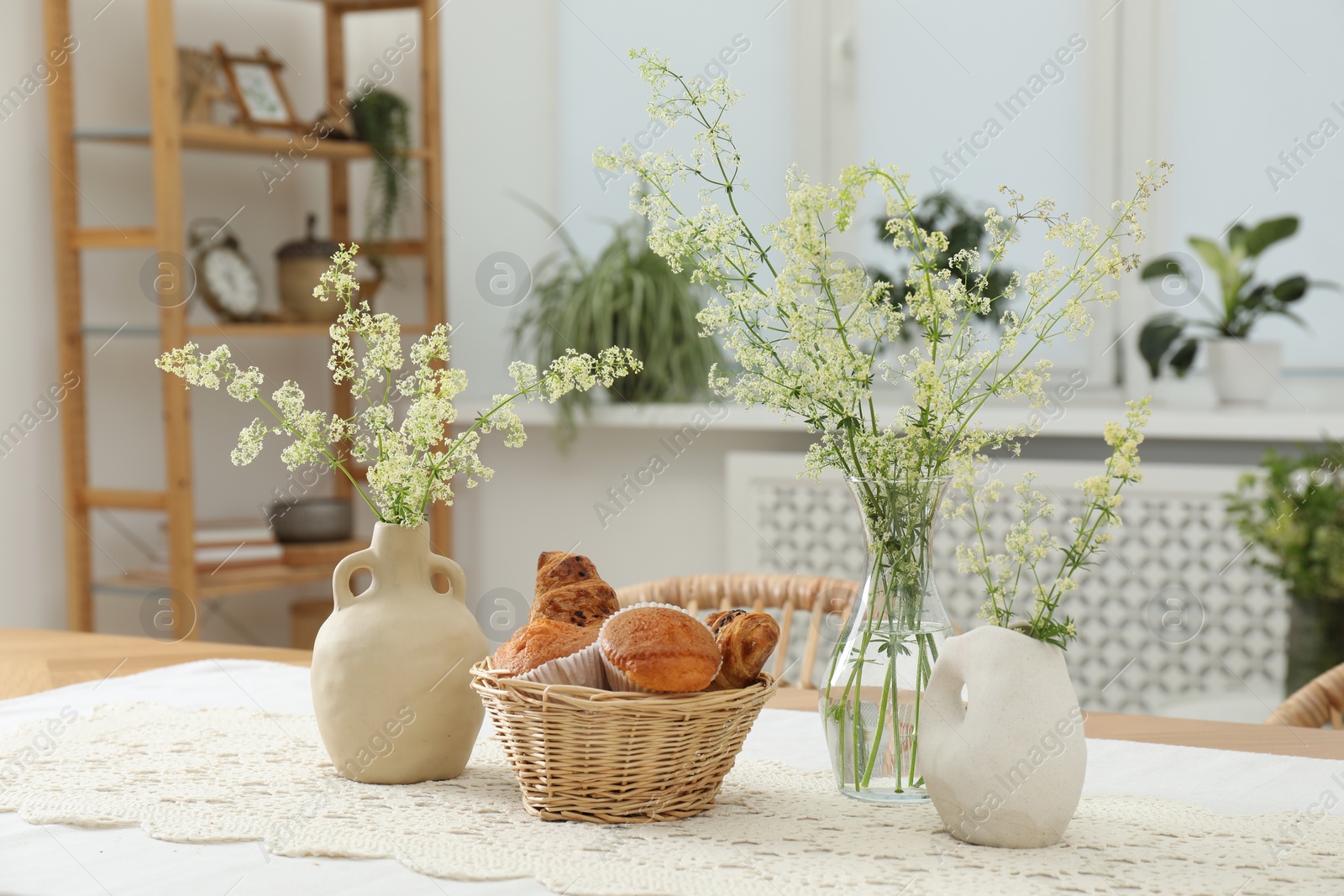 Photo of Fresh pastries and beautiful flowers on table in stylish dining room