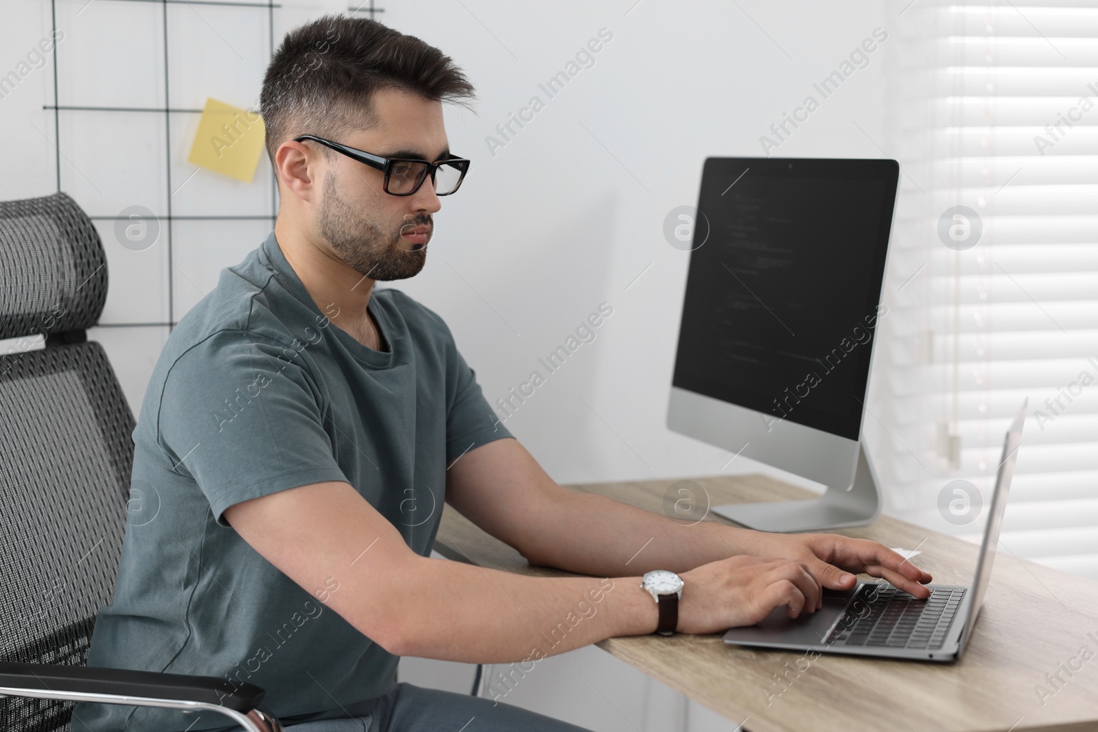 Photo of Young programmer working at desk in office