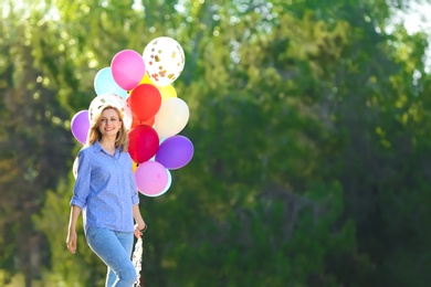 Photo of Young woman with colorful balloons in park on sunny day