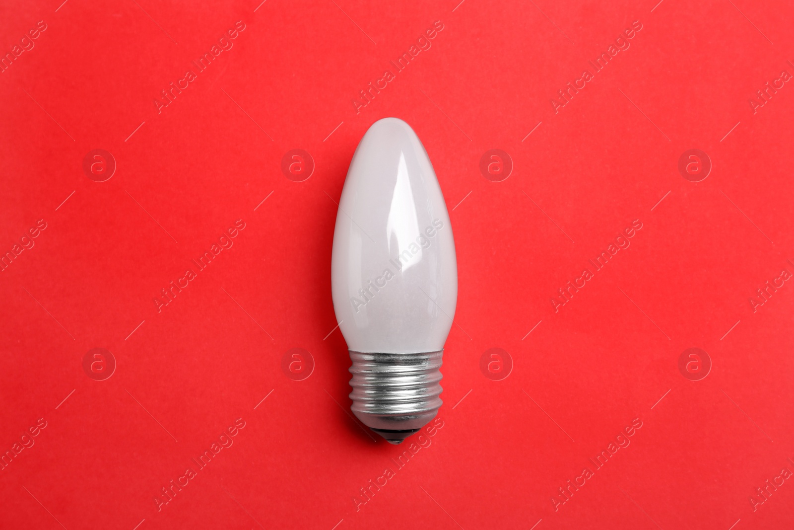 Photo of New modern lamp bulb on red background, top view