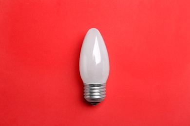 New modern lamp bulb on red background, top view