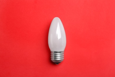 Photo of New modern lamp bulb on red background, top view