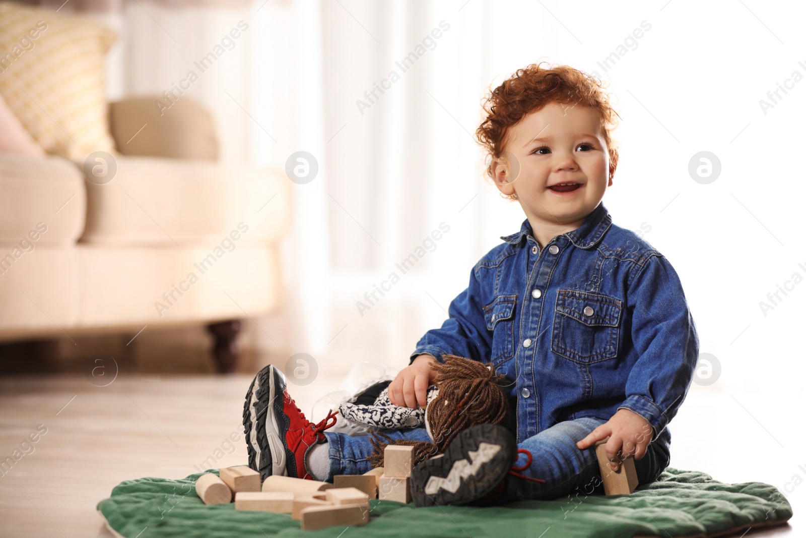 Photo of Cute little child playing with toys on floor at home