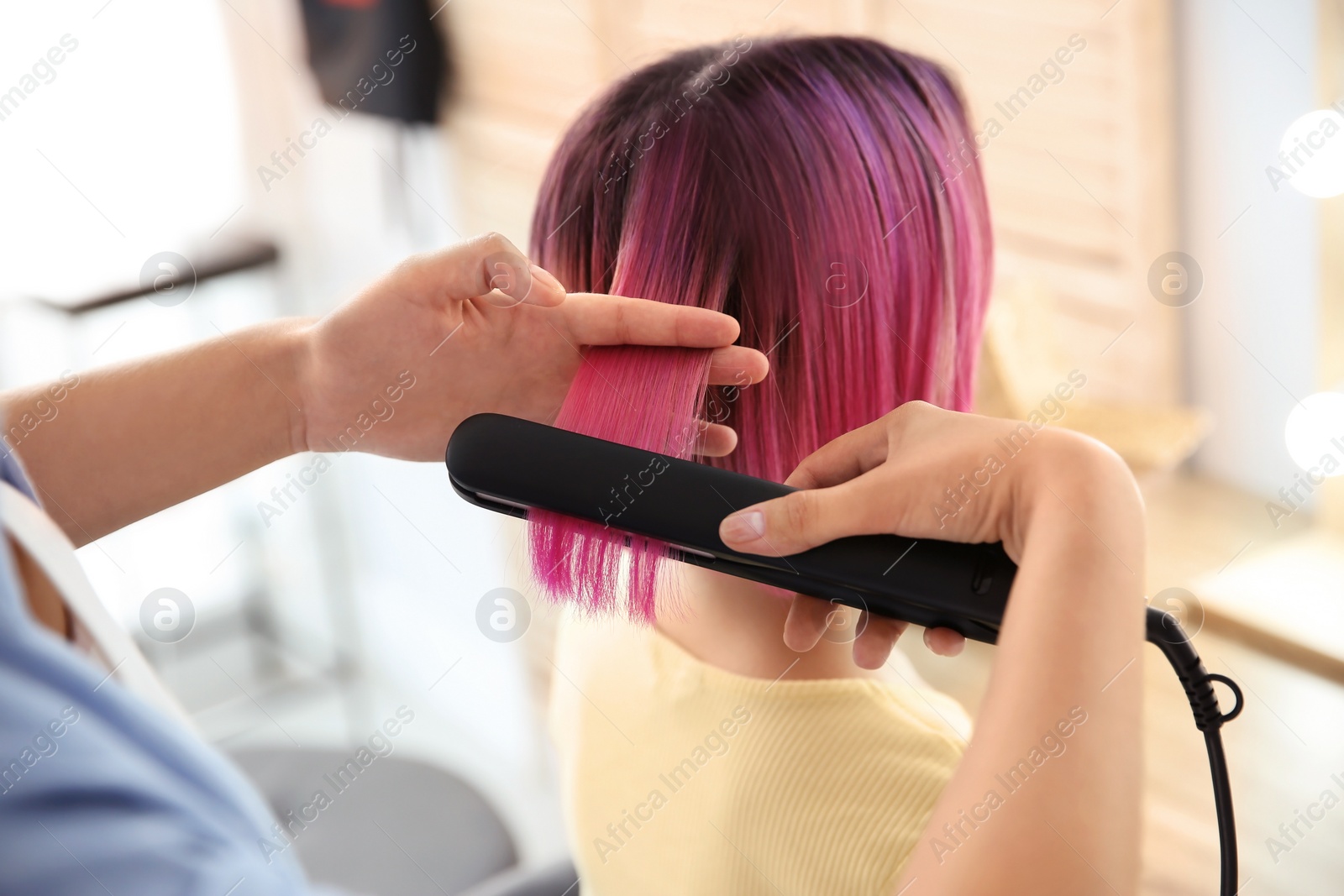 Photo of Professional hairdresser working with young woman in beauty salon. Trendy hair color