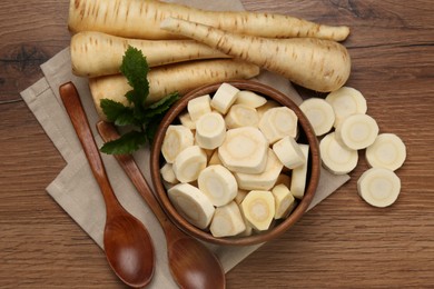 Flat lay composition with whole and cut fresh ripe parsnips on wooden table