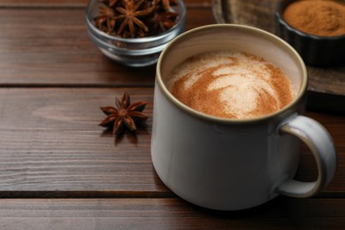 Photo of Cup of delicious eggnog with anise on wooden table. Space for text