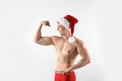 Young muscular man in Santa hat on white background