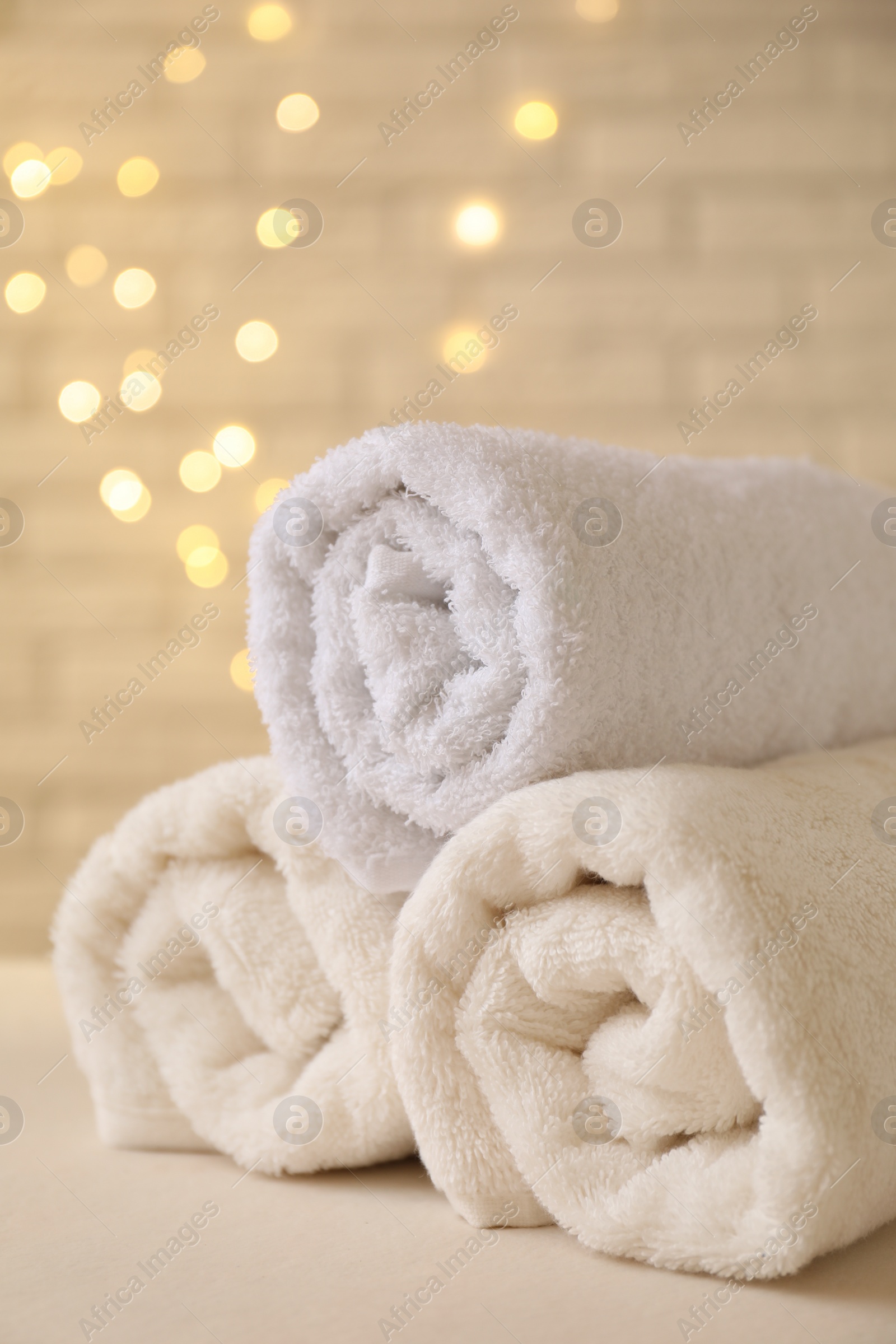 Photo of Rolled terry towels on white table near brick wall indoors