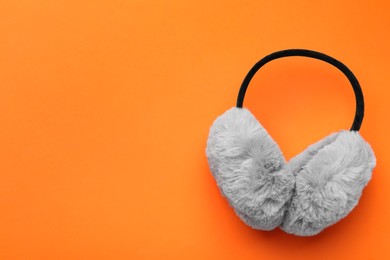 Photo of Stylish winter earmuffs on orange background, top view. Space for text