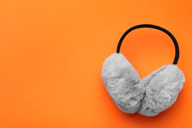 Stylish winter earmuffs on orange background, top view. Space for text