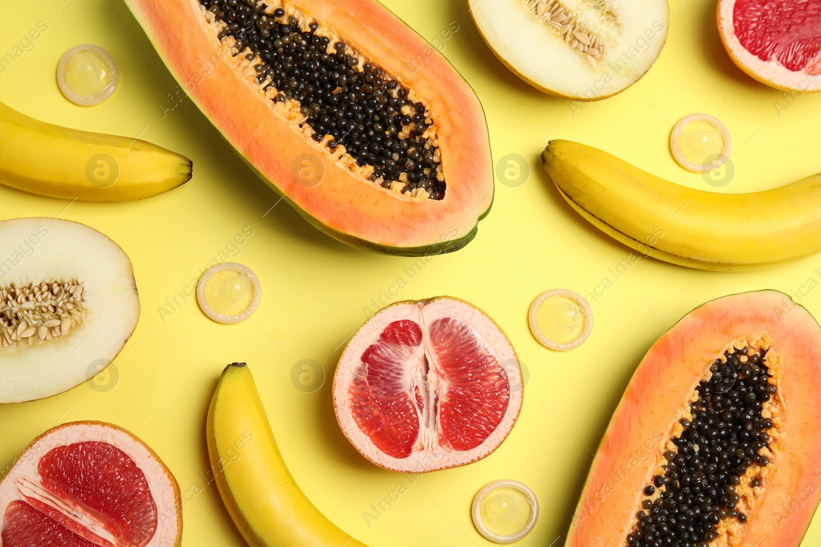 Photo of Flat lay composition with condoms and exotic fruits on yellow background. Erotic concept