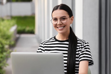 Happy young woman using modern laptop outdoors