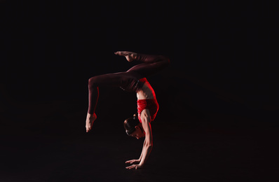 Photo of Young woman performing acrobatic element on stage indoors