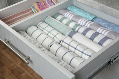 Photo of Open drawer with folded towels. Order in kitchen