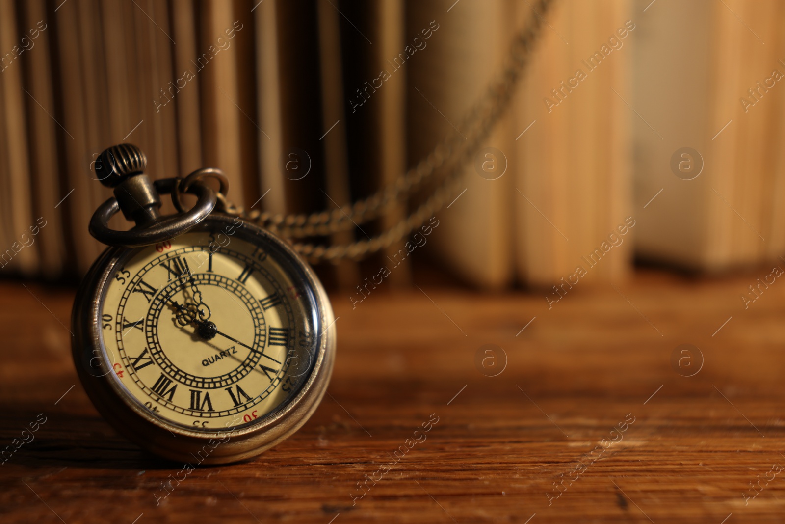 Photo of Pocket clock with chain on wooden table, closeup. Space for text