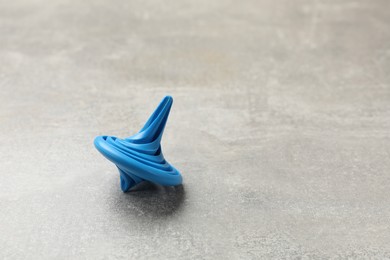 Photo of Blue spinning top on grey textured background, closeup. Space for text