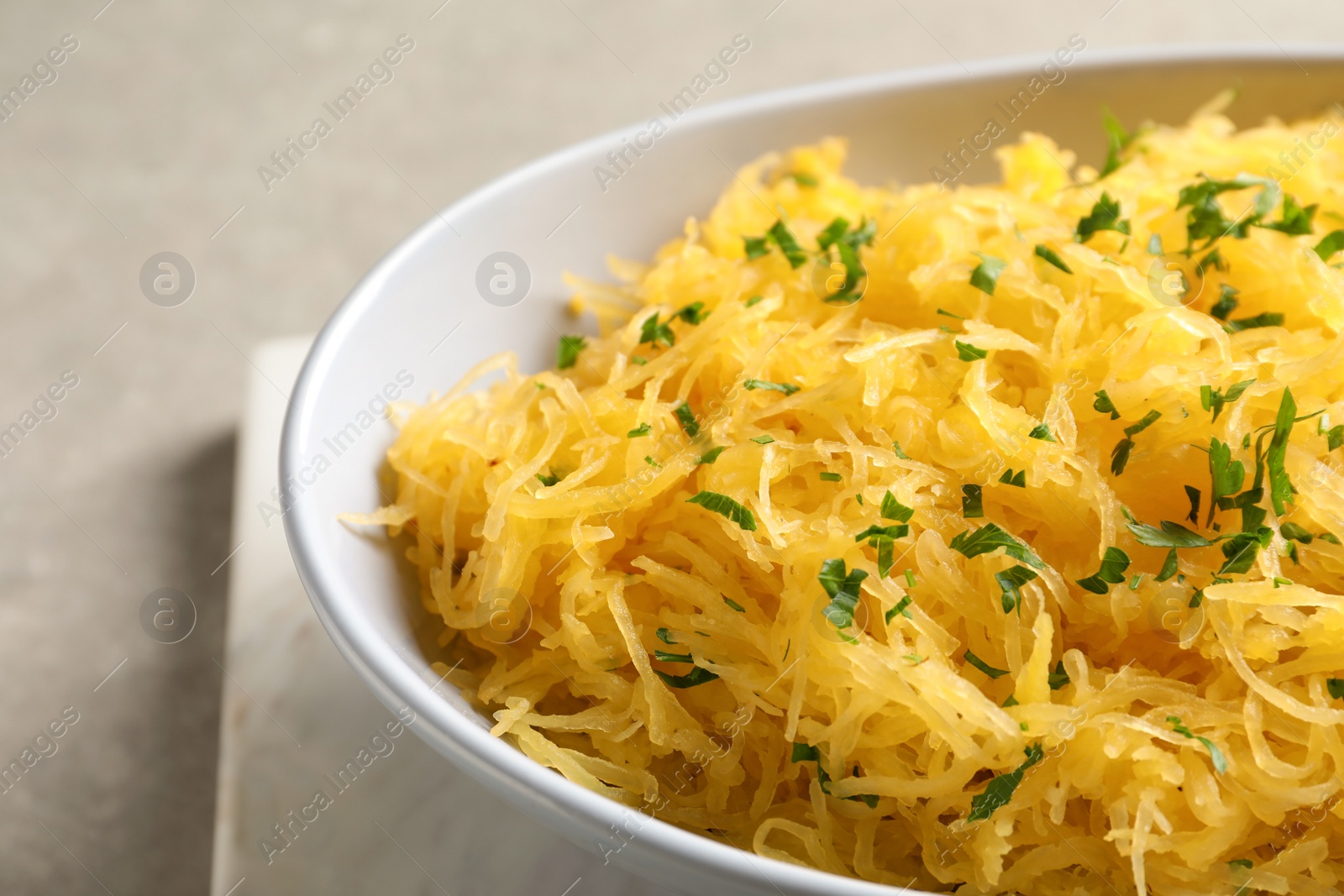 Photo of Bowl with cooked spaghetti squash on light background, closeup