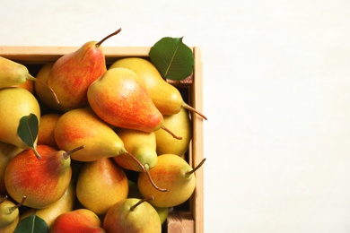 Photo of Wooden crate with ripe pears on light background, top view. Space for text