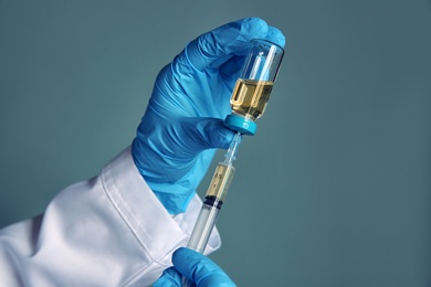 Photo of Doctor with syringe and medicine for vaccination on color background