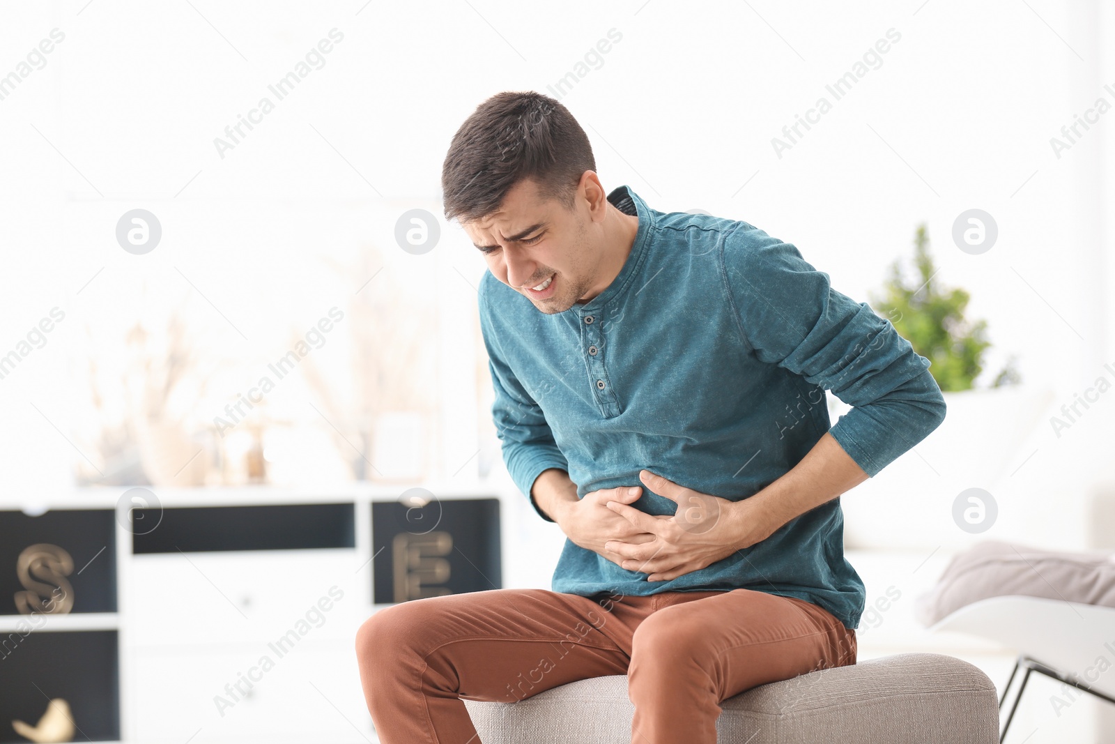 Photo of Young man suffering from stomach ache at home