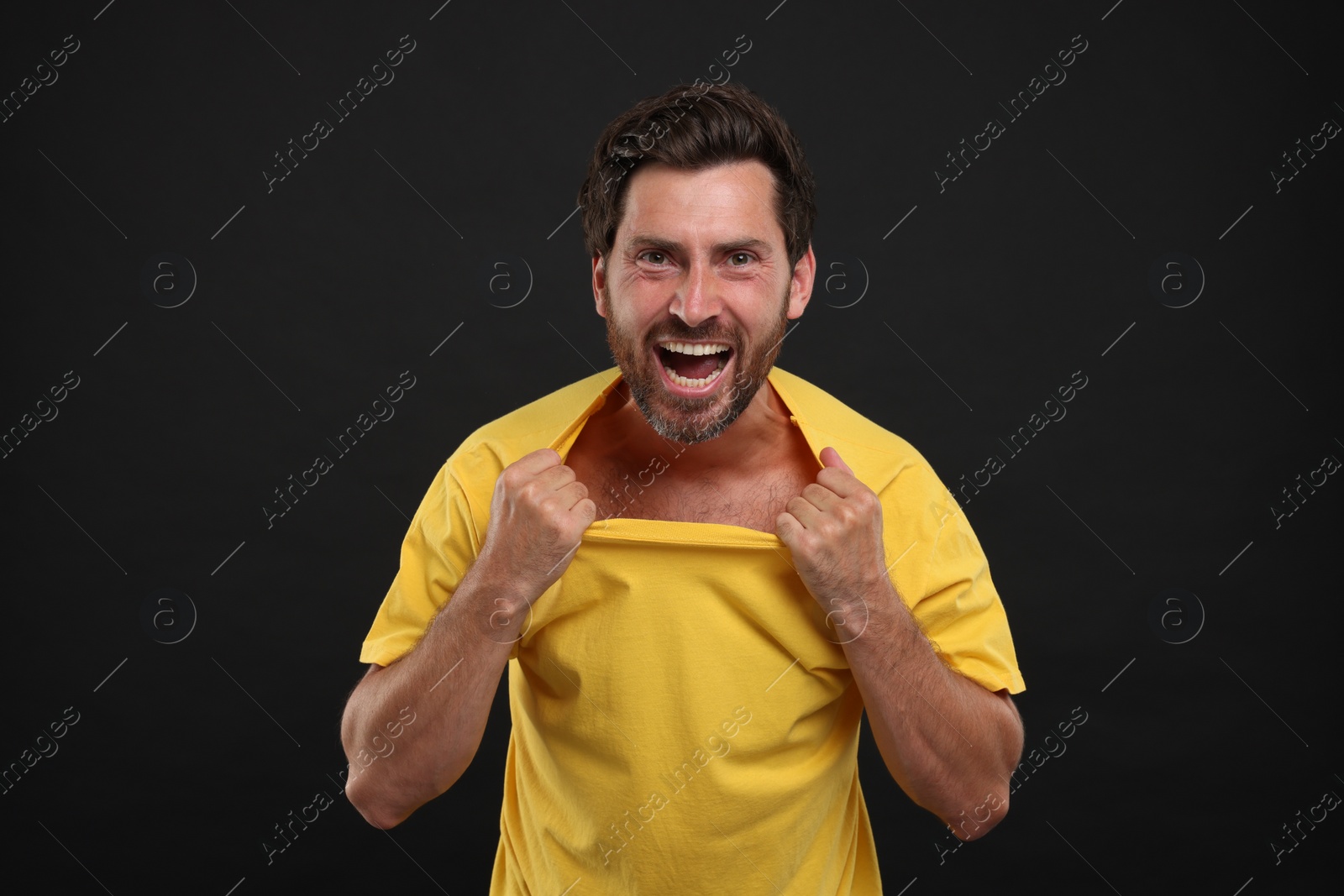 Photo of Emotional sports fan celebrating on black background