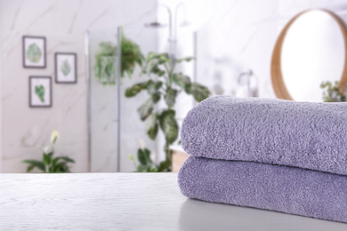 Image of Fresh towels on white wooden table in bathroom. Space for text