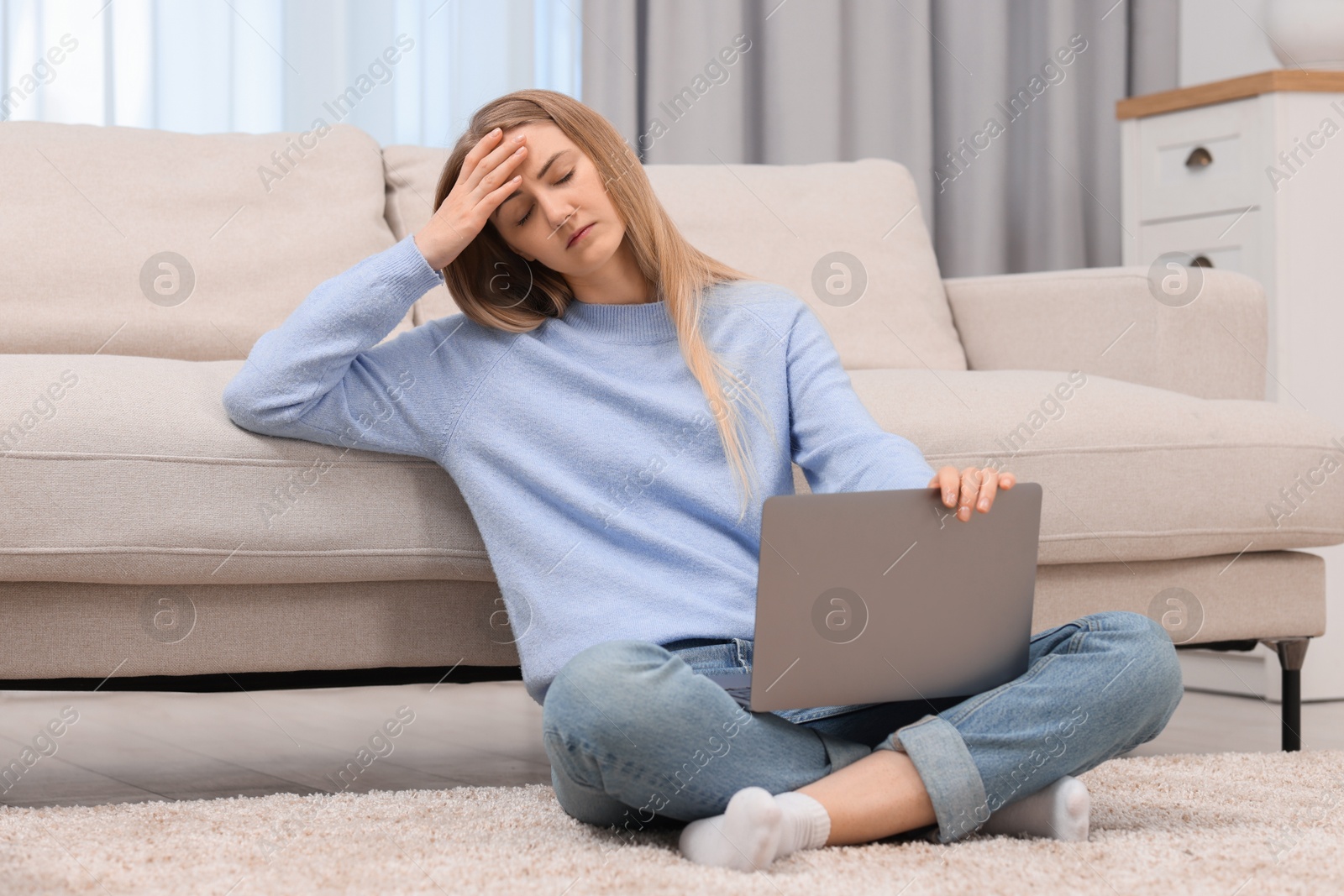 Photo of Overwhelmed young woman sitting with laptop on floor at home