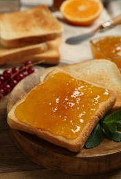 Photo of Delicious toasts with jam and mint on wooden table, closeup